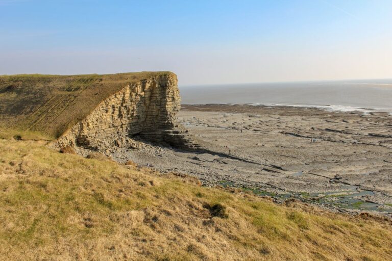 A cliff and a long rocky reef beach in Wales