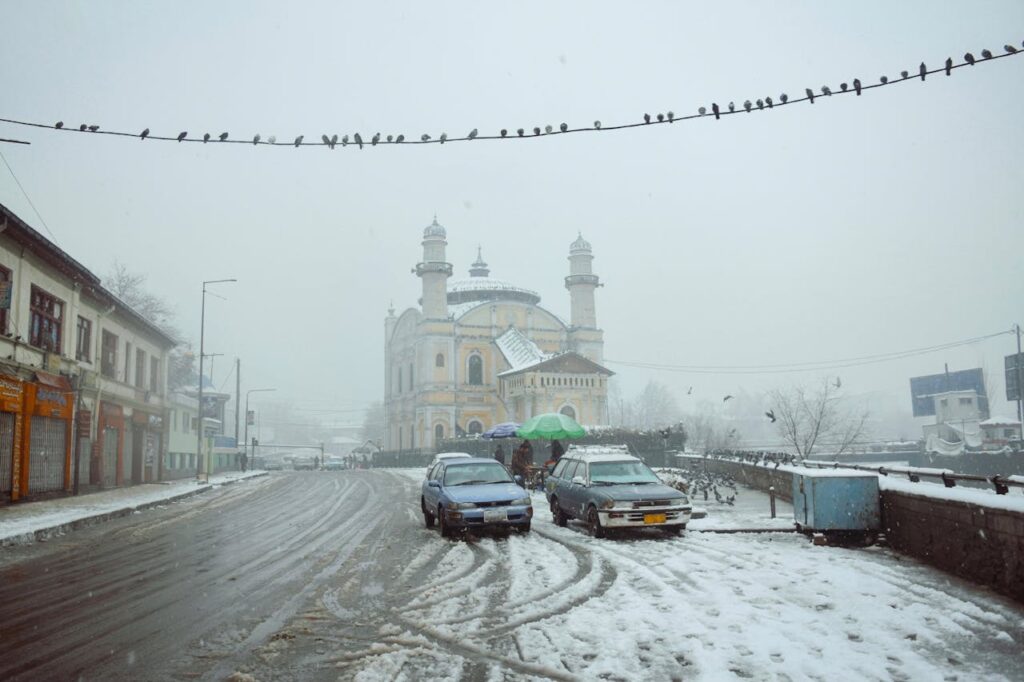 A snowy place in Afghanistan, featuring some cars and a building.