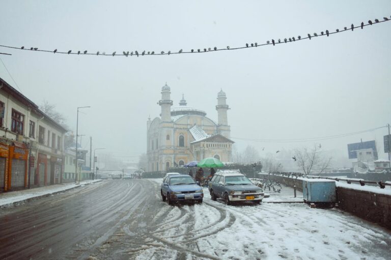 A snowy place in Afghanistan, featuring some cars and a building.