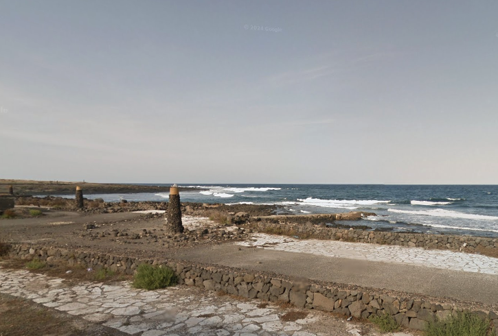 Some sidewalk infront of the open ocean with some small waves breaking