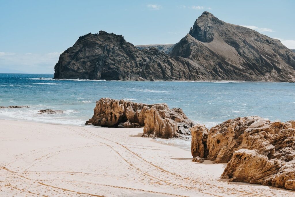 A beach of water rocks and sand.