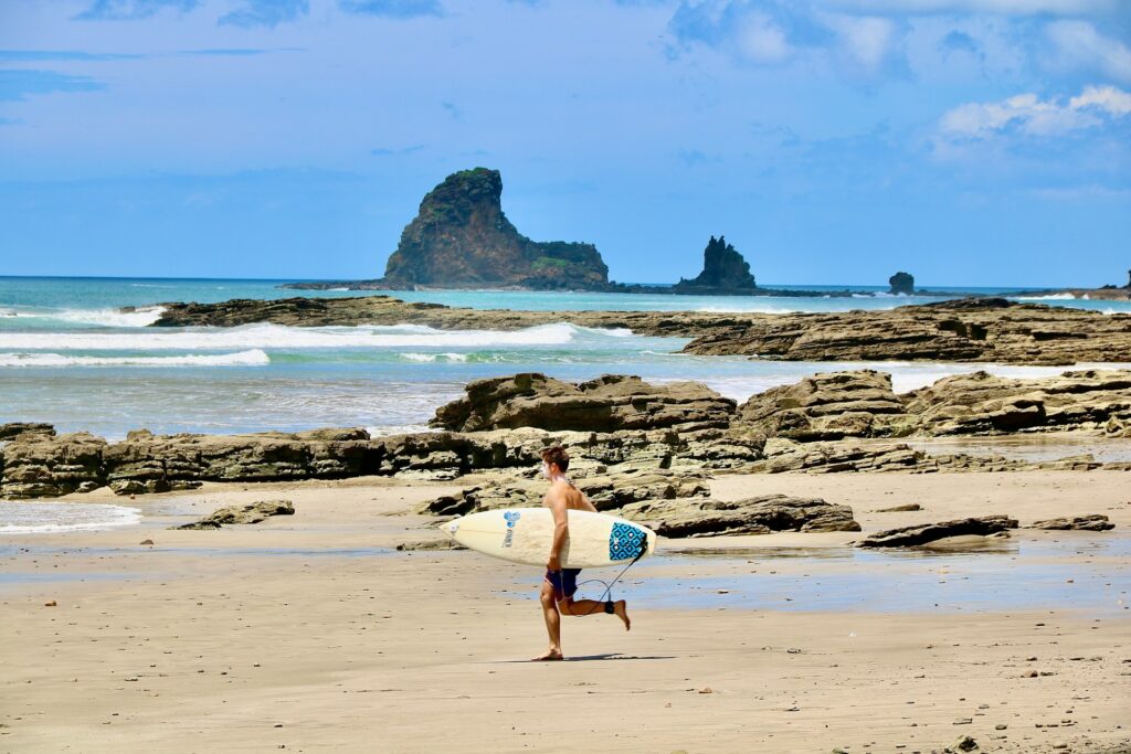 Photo of a surfer running on the beach of playa maderas