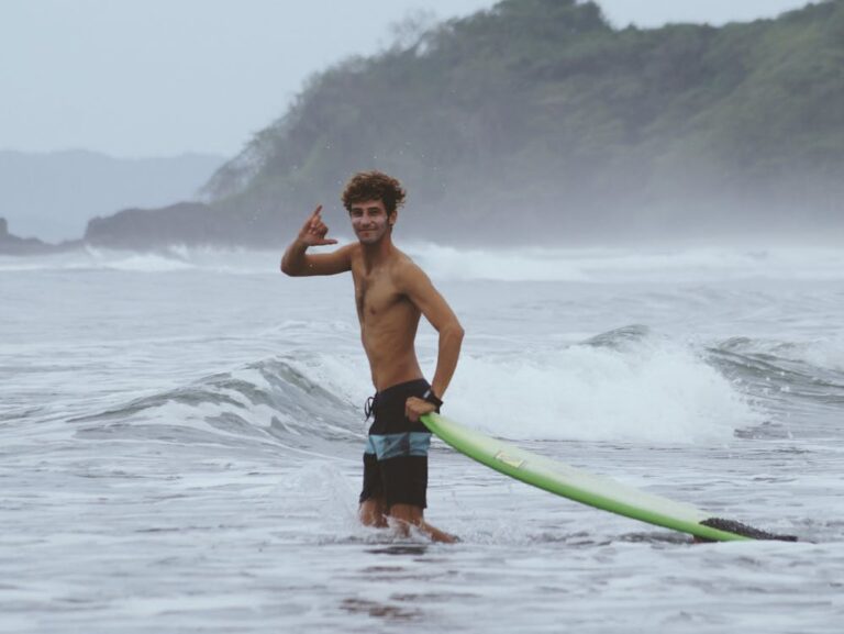 Surfer throwing a shaka when entering the water to surf