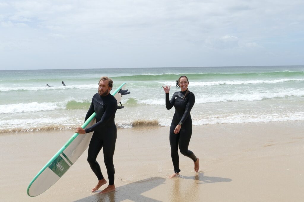 Co-Founder Matthew Davis, walking with a stoked student after scoring some fun waves.