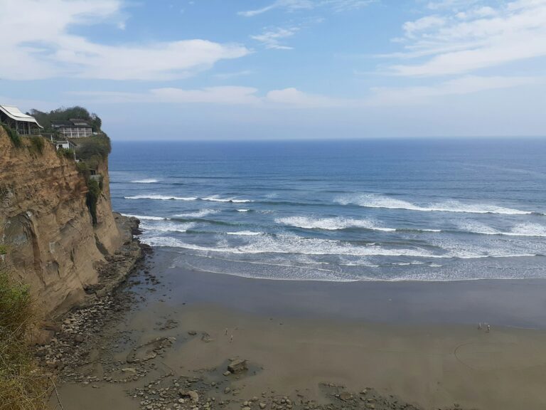 Photo of a big sea cliff with the ocean and waves breaking below