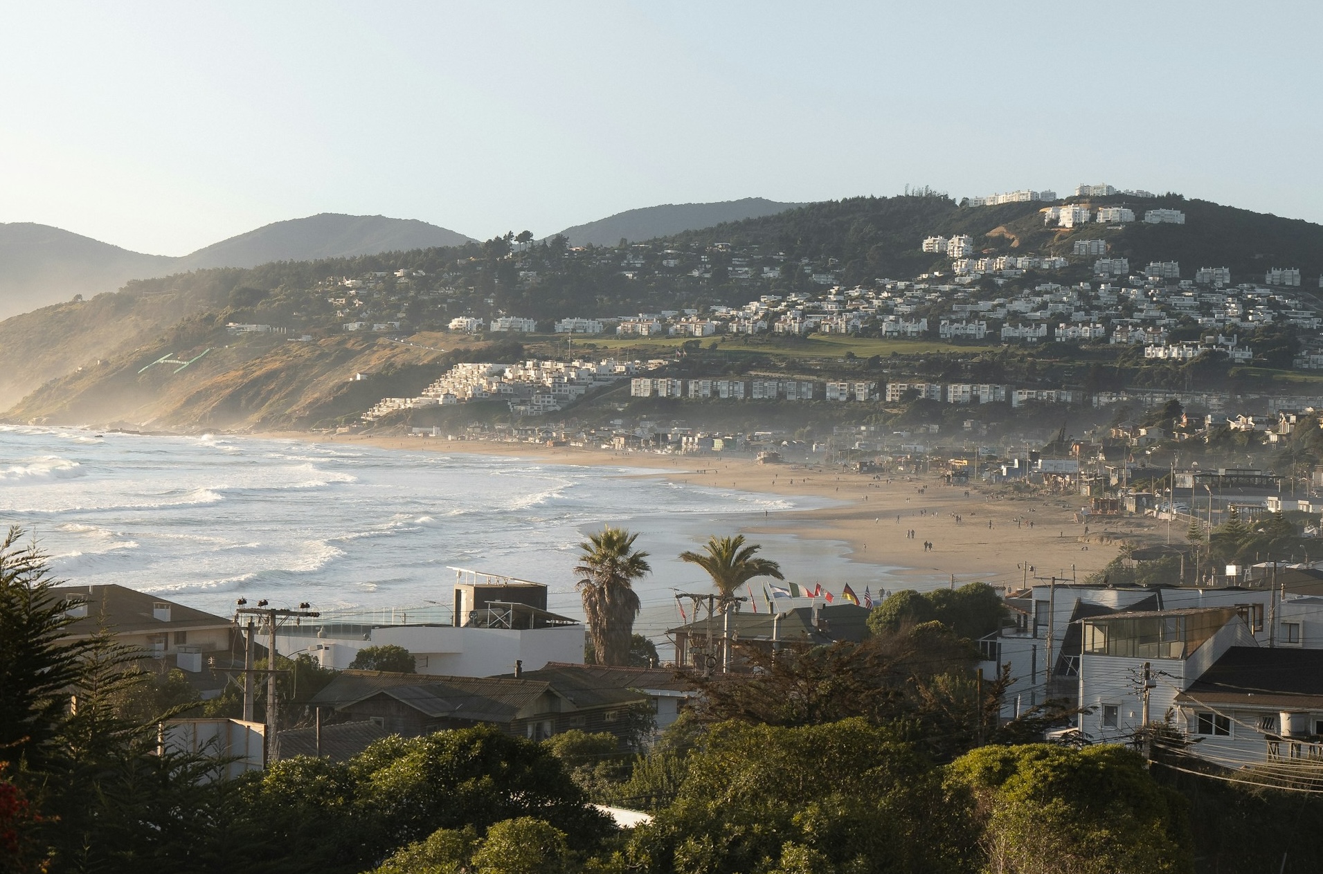 The city of Maitencillo with waves breaking, buildings, and greenery. 