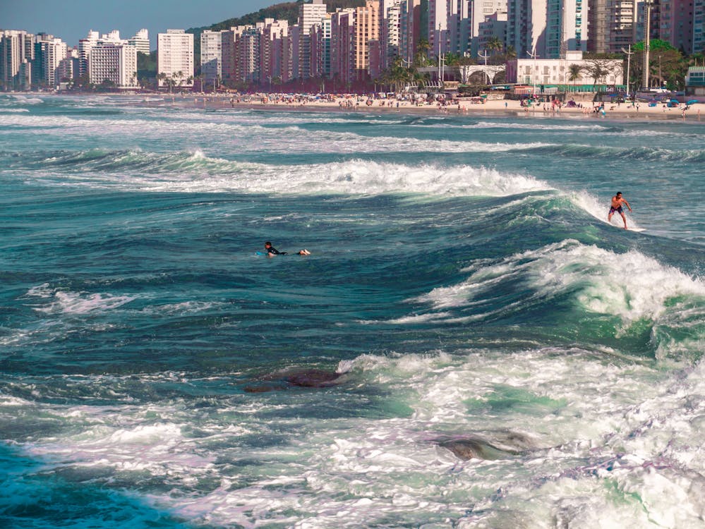 Surfer riding a wave with the city of Bertioga in the background