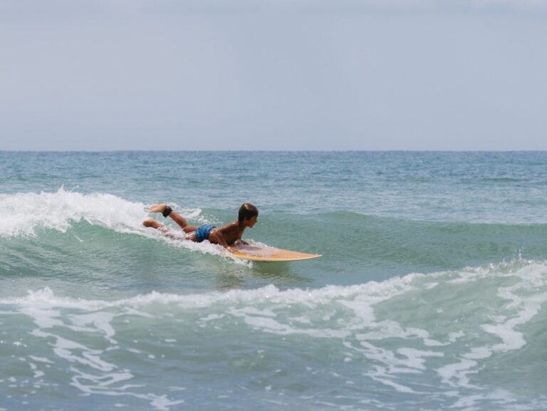 Young boy popping up a wave to surf