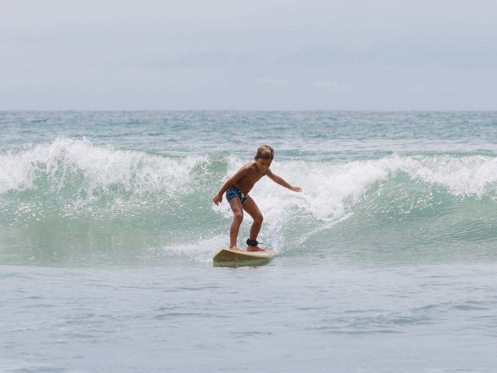 Little boy riding a wave while surfing