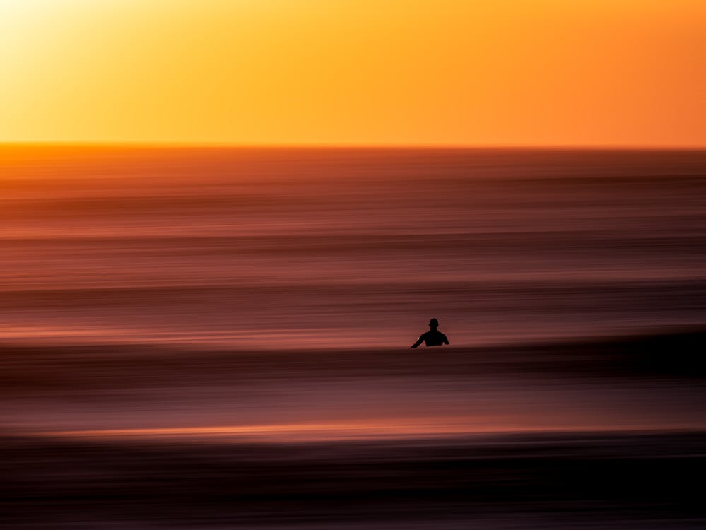 Beautiful photo of a surfer waiting for a wave at sunset