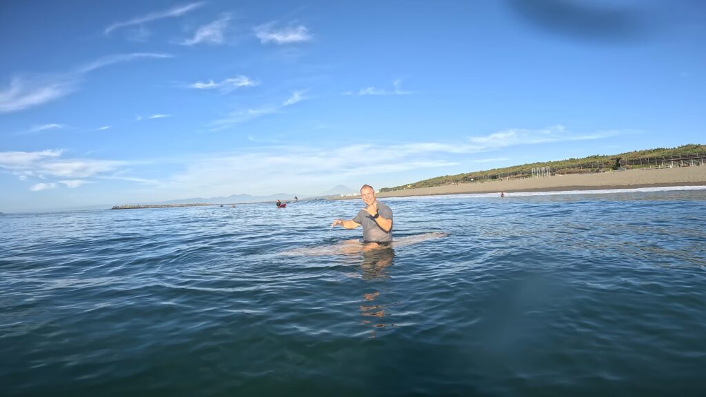 A stoked surf learner with an epic view in the background. Photo provided by Hosoii Surf & Sports.
