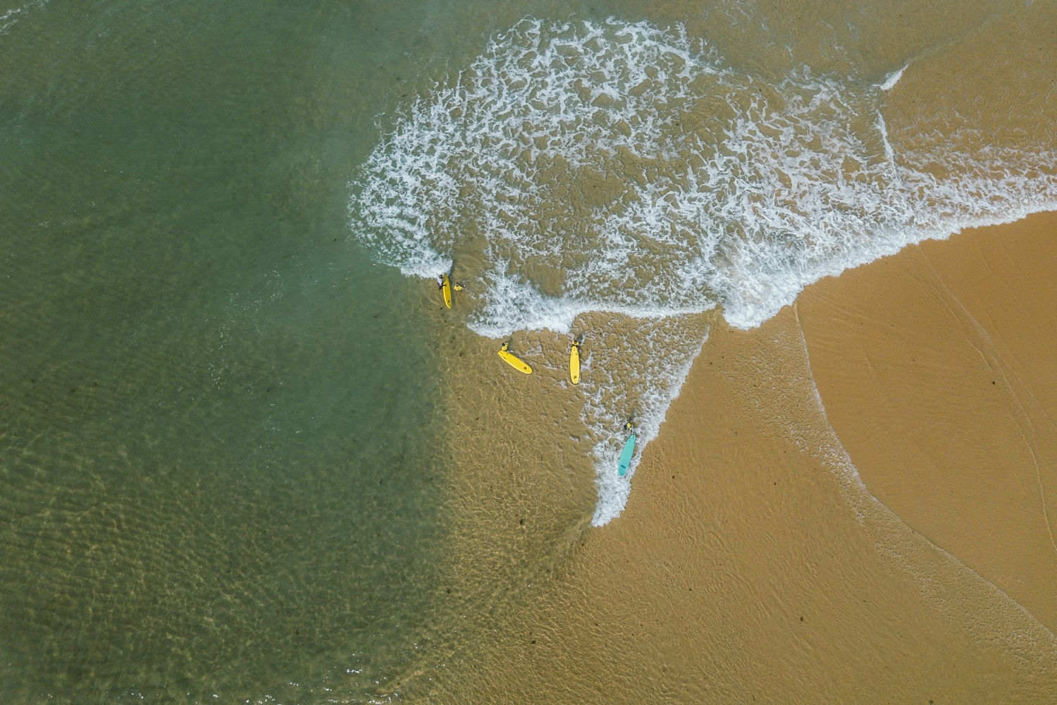 A group of Noah Surf House beginners enjoying some waves with crystal clear water.