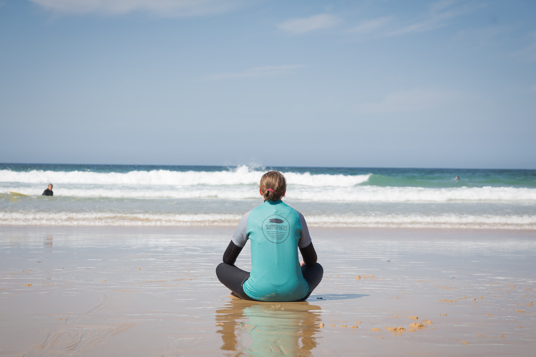 Sitting and watching the waves, somoene poses with a Surf Milfontes tshirt.