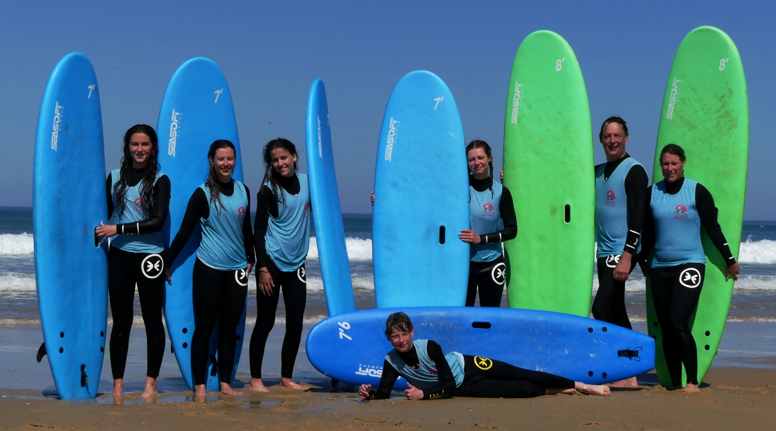 A group of lovely Ocean Lovers Surf School beginners with wide smiles post surf lesson.
