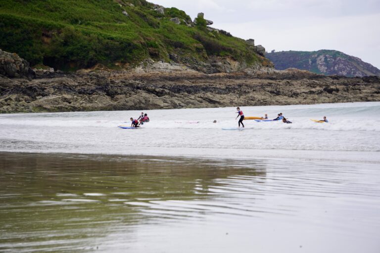 A group of surfers enjoying a lesson with Surfing Locquirec.
