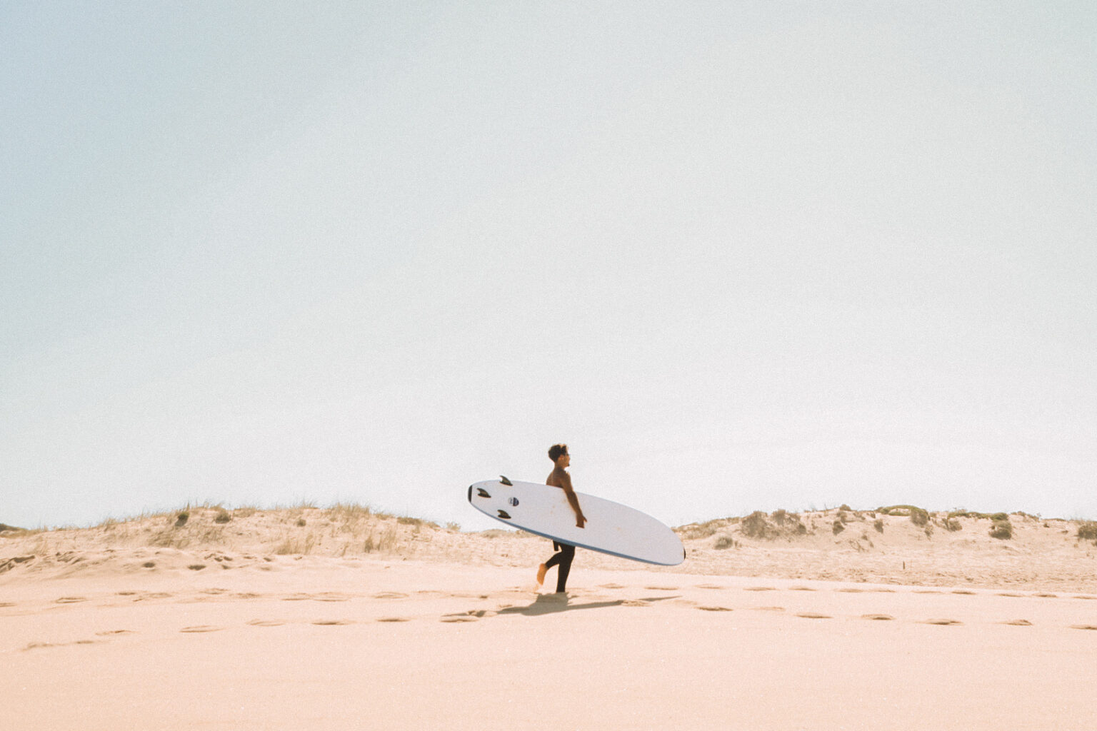 A surfer walking up the beach.