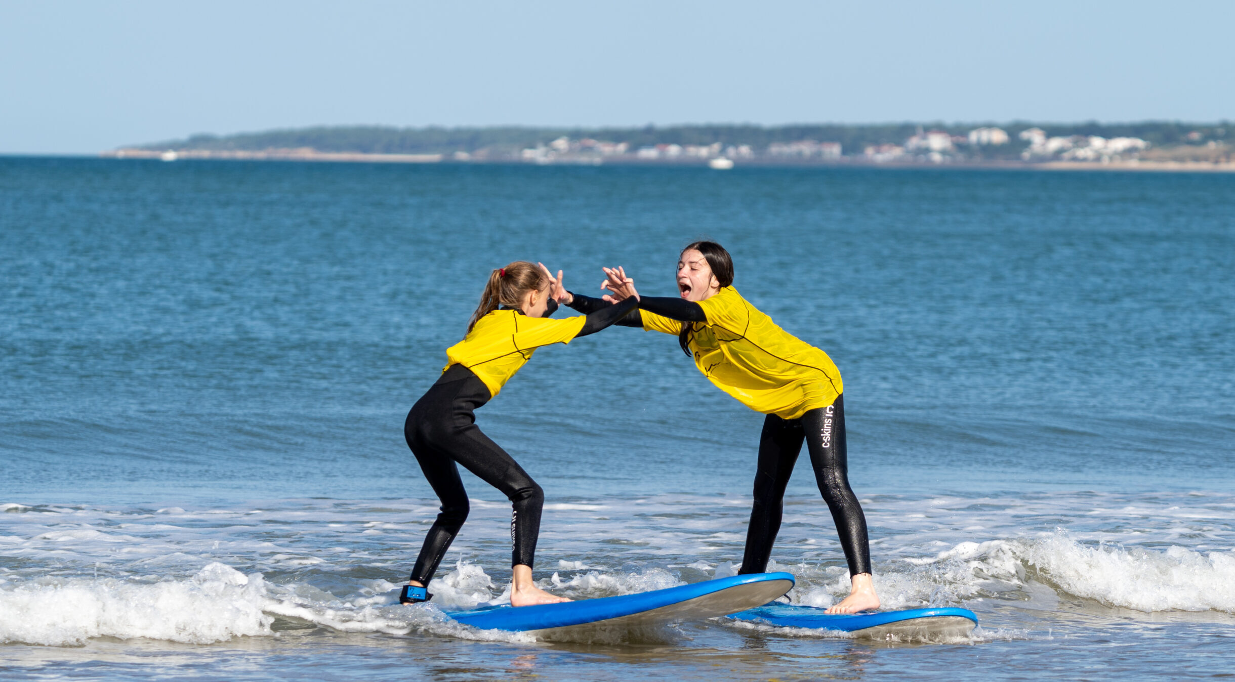 Two Manu Surf students connecting hands on a wave.