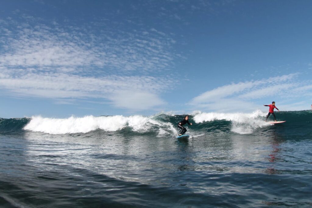 A surfer catching a wave with Kaizen Surf School