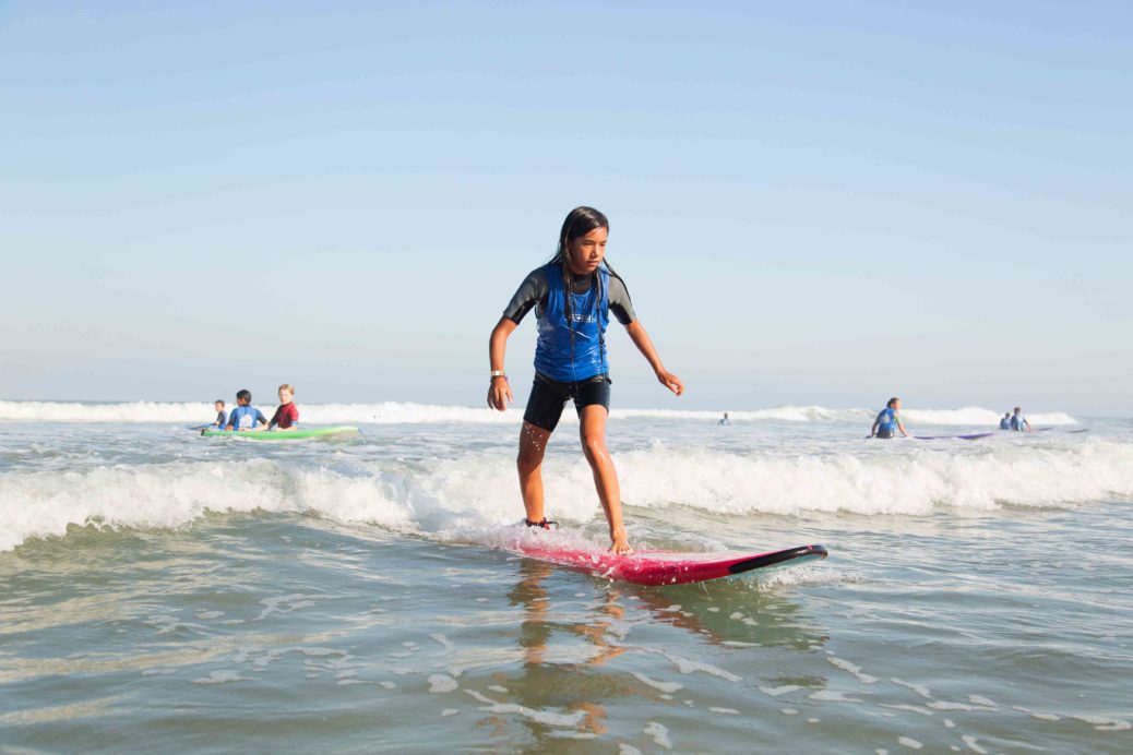 A grom enjoying a surf session and the thrill of riding a wave with OSC Surf School.