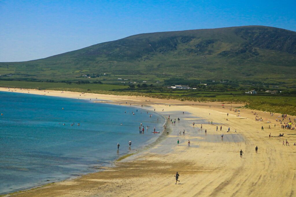 A overview of Inch beach with water, the backround hills, and people walking!