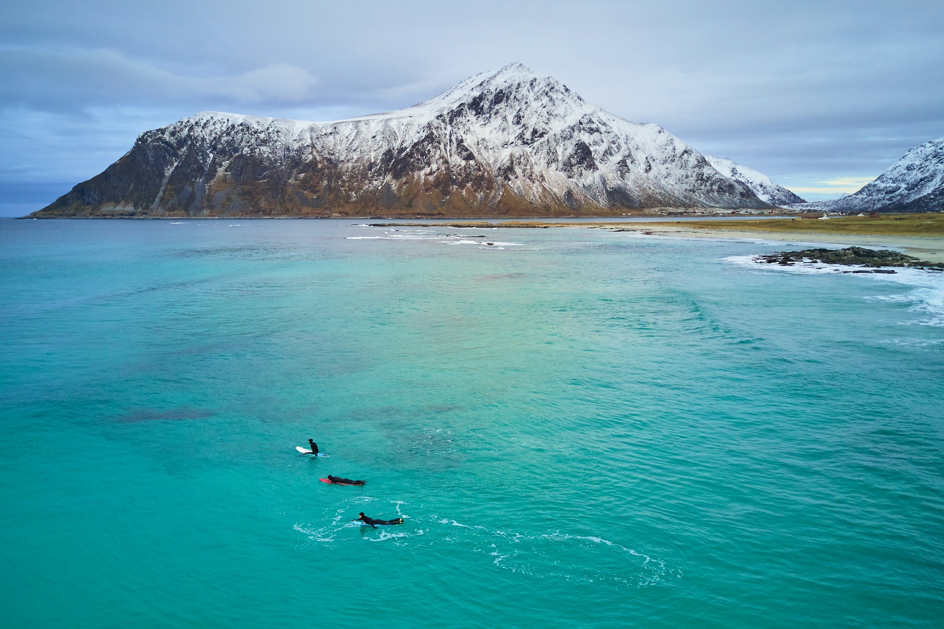 Flakstad Beach with some surfers out in the water searching for waves.