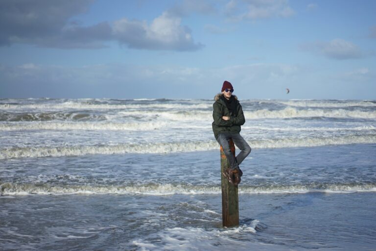 A person sitting on a pilling with waves breaking in the background.