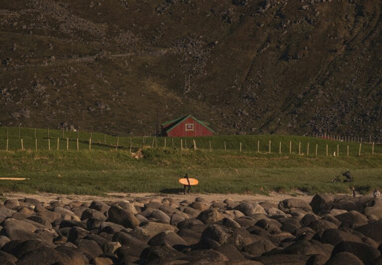 A surfer making the walk back to the warm home after a surf at Unstad Beach.