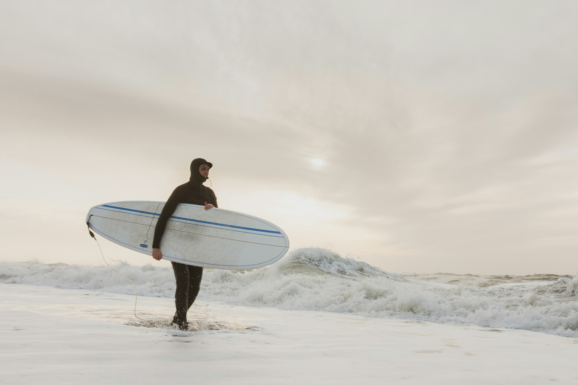 A surfer walking along the beach in Hvide Sande.