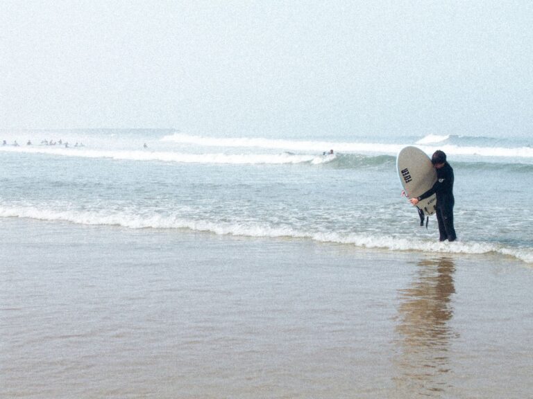 A surfer pictured wrapping their leash around their board along one of the many beaches in Espinho, Portugal