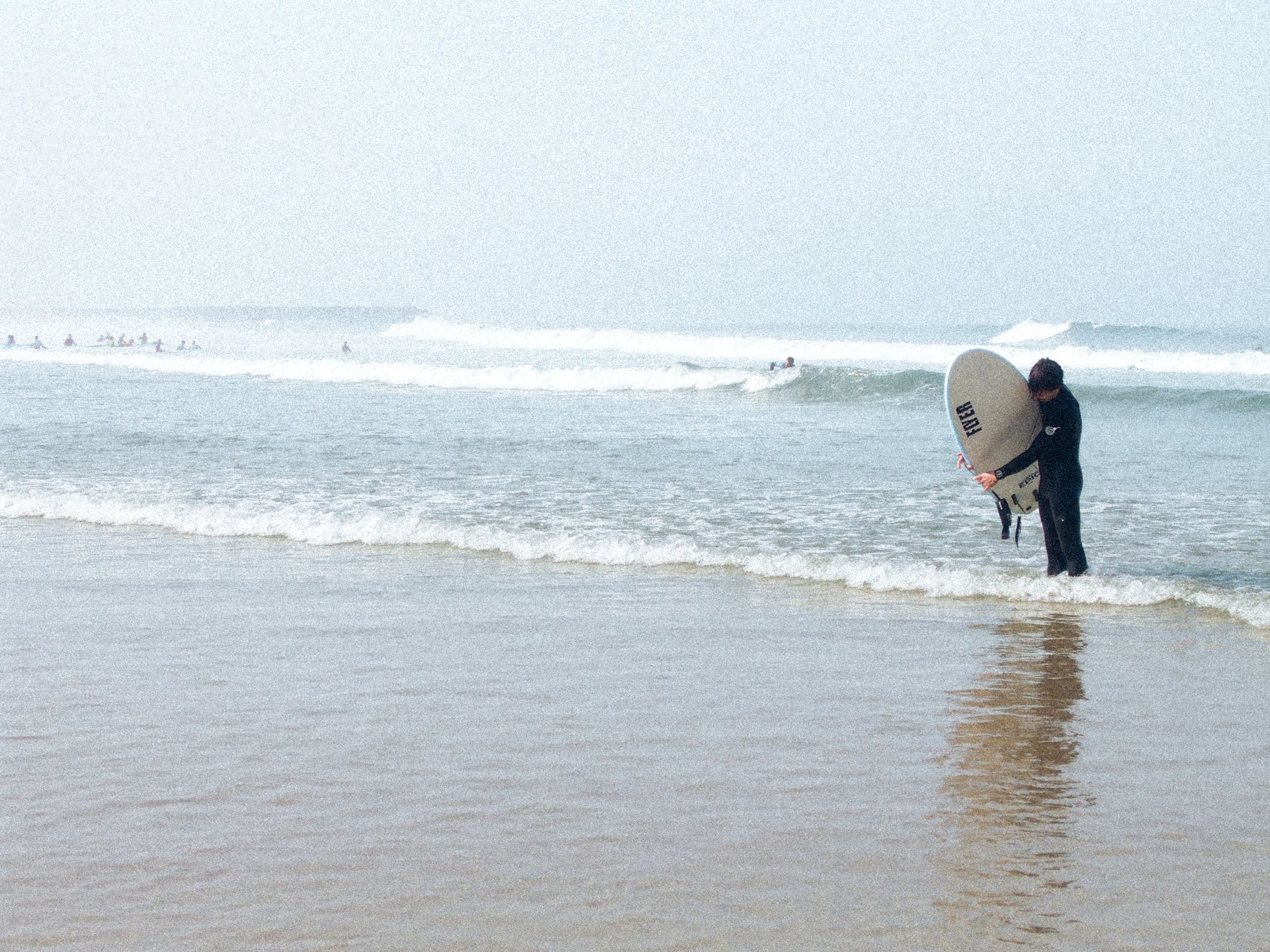 A surfer pictured wrapping their leash around their board along one of the many beaches in Espinho, Portugal