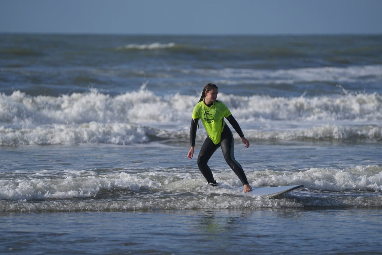 A student from The Pier Surf School enjoying a wave during a lesson.