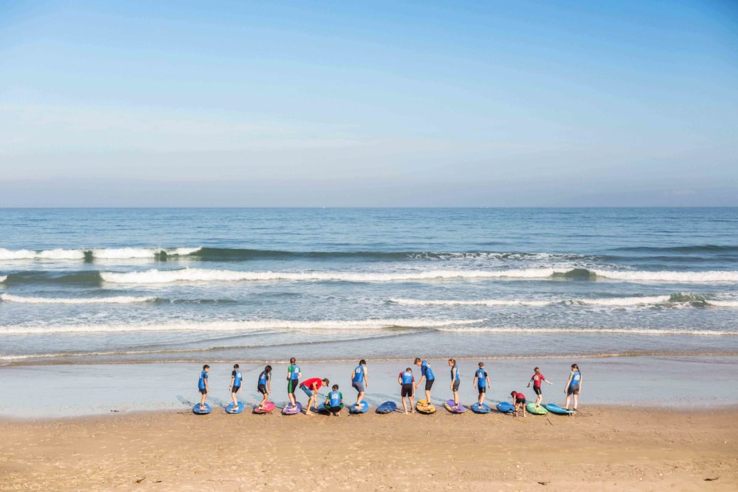 A photo of the OSC Surf School preparing to get into the water with all of their surf learners.