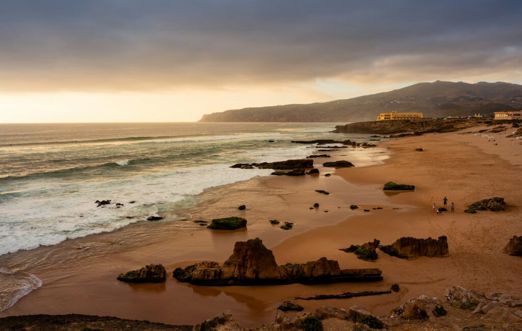 A beautiful sunset vibe over the Praia do Guincho with surfers in the water.