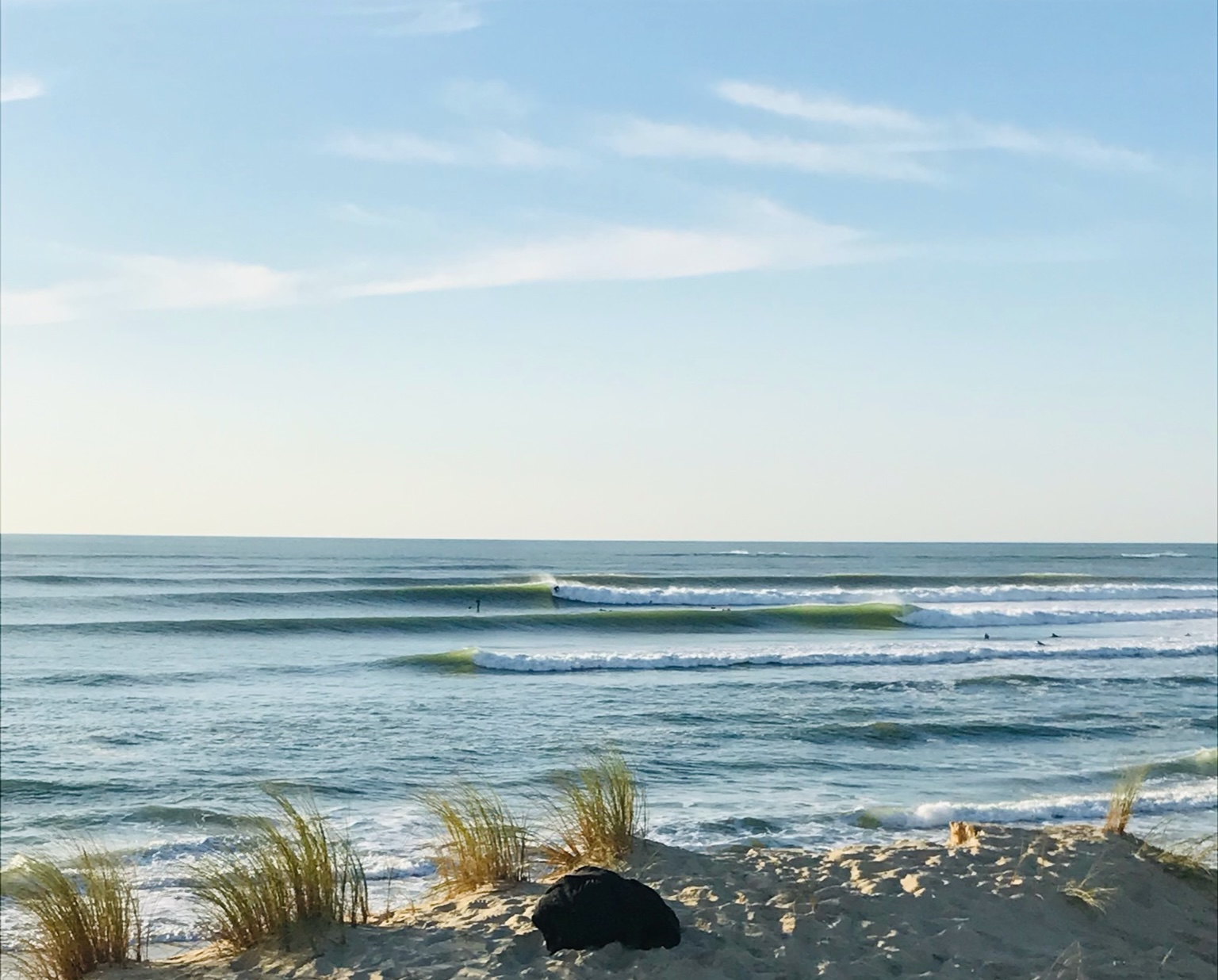 A beautiful landscape of some waves breaking in the background with surfers. Photo provided by Its On Surf School