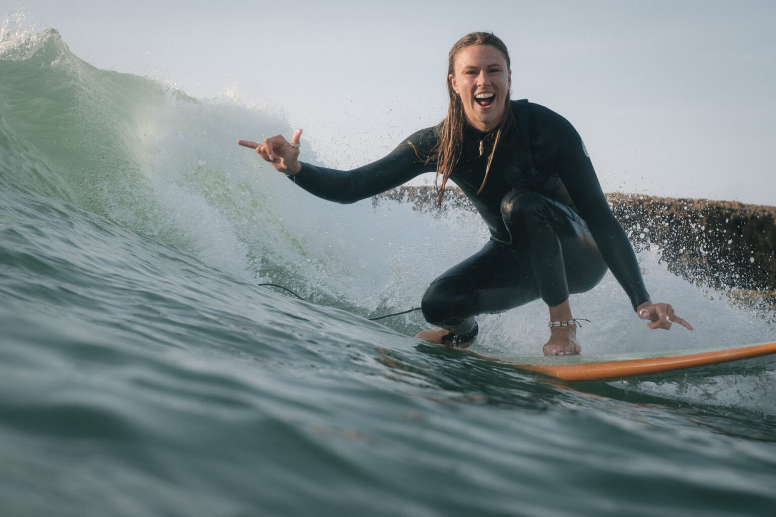 A visitor at La Crique Surf House enjoying a ride, while throwing up a shaka in Bouznika.