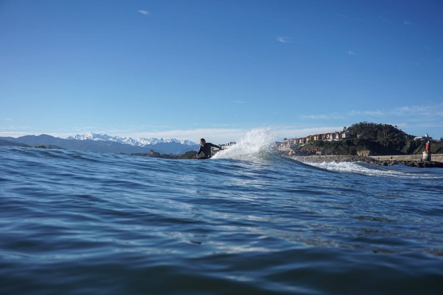 Someone taking some good lines on a wave with the Picos National Park in the background.